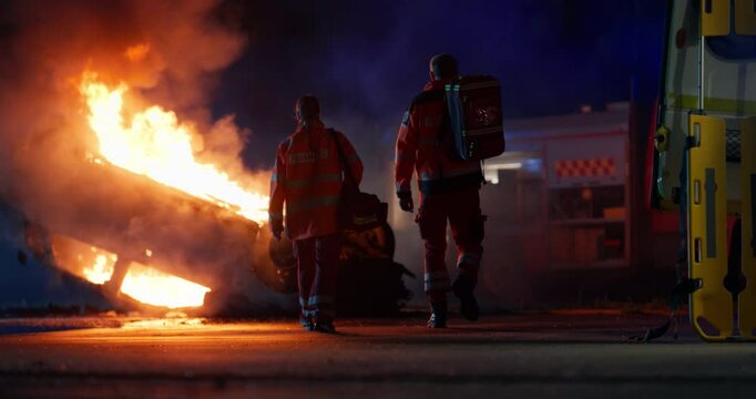 Portrait of an Emergency Medical Service Team Walking in High Visibility Medical Orange Uniform with "Paramedic" Text Logo. Two  Emergency Medical Technicians or Doctors at Work