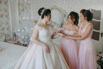 A bride and her bridesmaids are posing for a picture in a room with pink walls and pink dresses