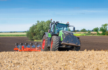 Obraz premium Tractor with 7-share reversible plow cultivating the field after the grain harvest - 2144
