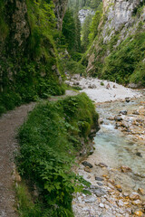 a small mountain stream flowing through a narrow gorge surrounded by steep cliffs and dense...