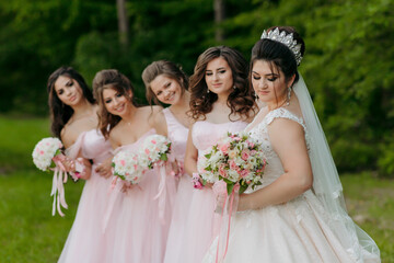A bride and her bridesmaids are posing for a picture. The bride is wearing a white dress and a...