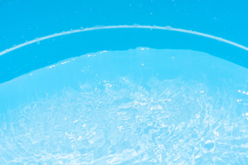 Blue water with ripples on the surface. Defocus blurred transparent blue colored clear calm water surface texture with splashes and bubbles. Water waves with shining pattern texture background.