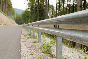 vista ampia, da vicino, di un guardrail che si estende in prospettiva lungo una strada asfaltata di...