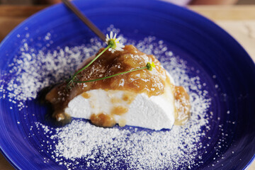 dettagli di un dolce alla crema con marmellata, docrato con due margherite, su un piatto blu