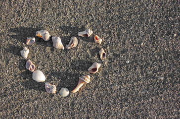 Heart shape made of shells on sea sand
