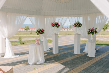 A white tent with pink flowers and white curtains