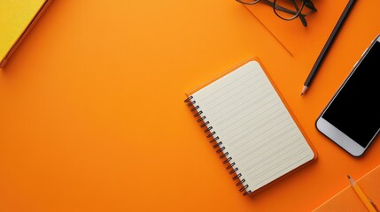 Bright orange desk background with a lined notebook, mechanical pencil, and smartphone on a vibrant orange surface