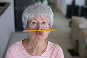 Senior woman holding a pencil between lips and nose