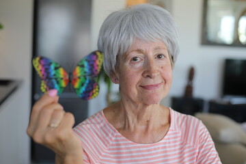 Senior woman holding stunning multicolor butterfly 