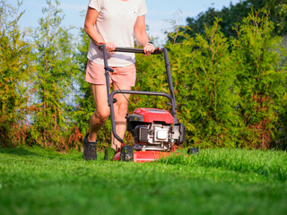 Woman mowing lawn with lawnmower in back yard