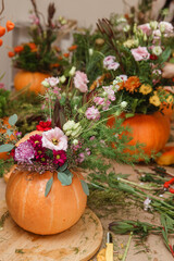 Flower arrangement in a pumpkin, autumn interior decor. Creating handmade autumn decor.