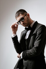 Handsome Man, Fashion model in black costume, tuxedo, bow tie and sunglasses