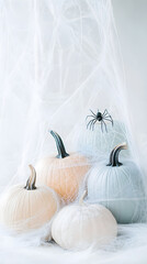 A minimalist halloween scene featuring soft pastel pumpkins arranged with a spider and delicate cobwebs, creating an eerie yet gentle atmosphere