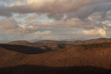 Fototapeta premium vista dettagliata su varie catene di montagne e alture nella Slovenia occidentale, vicino al confine Italiano, di pomeriggio, in inverno, al tramonto, sotto un cielo nuvoloso