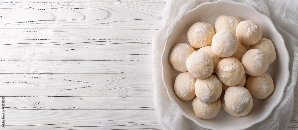 Poster top down view of scrumptious dough balls in a baking dish on a white wooden surface with ample space