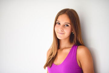 portrait of a 14 years old teen girl close to a white wall with colored shirt