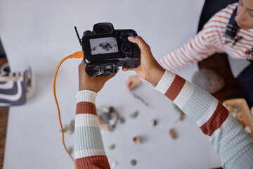 Top view closeup of female hands holding professional camera during product photography photoshoot...