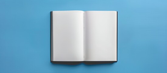 Top down flat lay of an open blank white book on a blue desk with copy space image