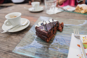 fetta di torta al cioccolato e panna, su un piatto trasparente e un caffè espresso, su un tavolo...