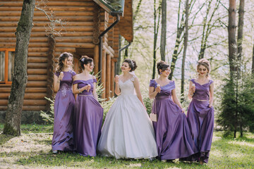 A group of women are walking in a forest, with one of them wearing a white dress. They are all...