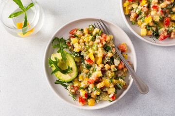 Enjoy a nutritious salad of boiled millet, chickpeas, fresh vegetables, and avocado, topped with olive oil, perfect for a wholesome vegetarian diet rich in vitamins and minerals