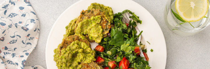 This nutritious breakfast features savory zucchini pancakes with green pea pesto, paired with a mixed salad of garden-fresh vegetables and herbs for a wholesome morning meal, banner