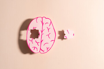 Human brain anatomy missing a piece of jigsaw puzzle on cream background. Concept of memory loss,...
