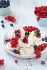 White sweet traditional merenques with berries on the plate