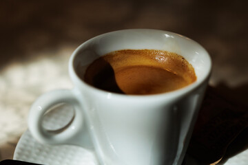 vista macro di una tazzina bianca riempita con del caffè espresso, su un tavolo, di giorno, a pranzo