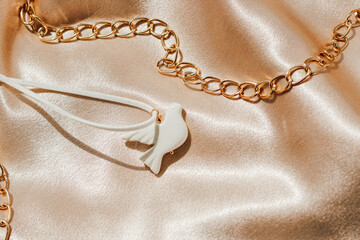 bijouterie white bird made of polymer clay on the background of silk shiny fabric