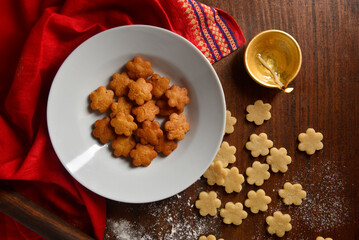 Homemade traditional cookies made during festival of Diwali. A bowl of deep fried cookies with Diya shot from above.
