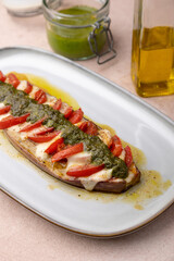 Baked eggplant with mozzarella cheese, tomatoes and pesto sauce. Traditional homemade seasonal dish. Grilled stuffed eggplant. Hearty summer dish. Selective focus, close-up.