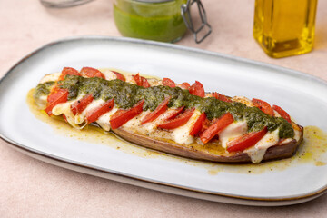 Baked eggplant with mozzarella cheese, tomatoes and pesto sauce. Traditional homemade seasonal dish. Grilled stuffed eggplant. Hearty summer dish. Selective focus, close-up.