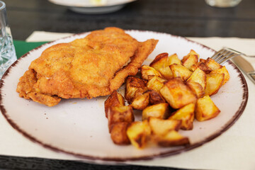 dettagli di un piatto con una bistecca impanata e patate al forno