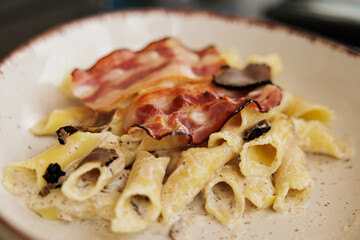 piatto di pasta con fette di pancetta e crema di tartufo