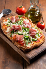 Pinsa condita con prosciutto crudo, parmigiano, rucola, sugo e mozzarella, cibo italiano