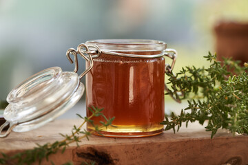Thyme herbal syrup in a glass jar on a table. Natural remedy for cough.