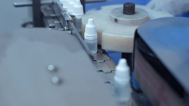 eye drop manufacturing. Ophthalmic drops solution, eye ear drop making process in factory. eye drop medicine in plastic bottles on conveyor belt. production of medical drops in a pharmaceutical line	