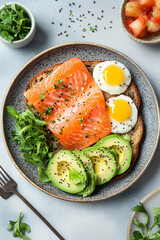 Top View Healthy Breakfast Composition. Top view of a healthy breakfast plate with avocado, smoked salmon, eggs, and greens.