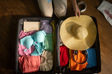 Woman organizes clothes and accessories inside a suitcase, meticulously preparing for an upcoming trip. Careful packing ensures a smooth travel experience and efficient use of space