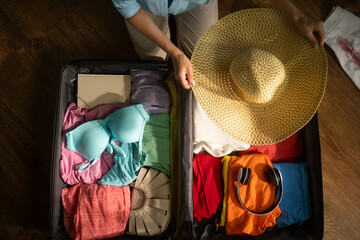 Woman organizes clothes and accessories inside a suitcase, meticulously preparing for an upcoming...