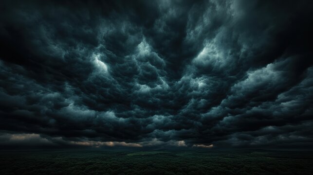 Dramatic aerial view of dark, turbulent storm clouds rolling over a dense forest, creating an intense and ominous atmosphere.