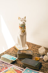 Set of a tarot reader on a table featuring various tarot decks, crystals, and a decorative cat
