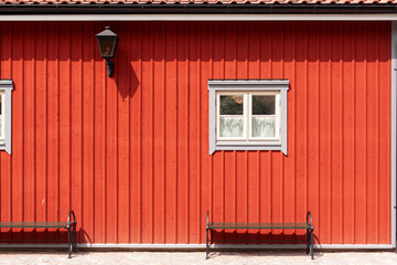 Rote Hausfassade mit kleinem weißem Fenster. Skandinavische Architektur. Red house facade with small white window. Scandinavian architecture.