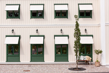 Grüne Fenster vor weißer Holzfassade. Skandinavische Architektur. Green windows in front of a white wooden façade. Scandinavian architecture.