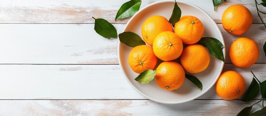 Tangerines mandarins with leaves arranged on a white plate against a wooden background Represents Christmas food top view copy space