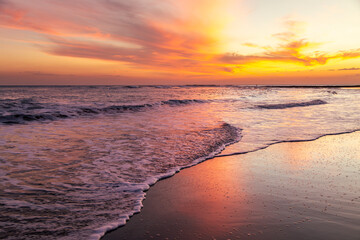 Serene sunset at Playa El Tunco, El Salvador, with gentle waves reflecting vibrant orange and pink hues. A tranquil seascape capturing the peaceful beauty of this popular coastal beach destination.
