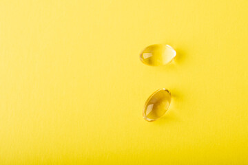 Vitamin C, omega 3 fish oil close up. Supplement soft capsule isolated on yellow background. Cod liver oil closeup. Vitamins in soft capsule. Healthcare concept. Copy space, banner. High quality photo