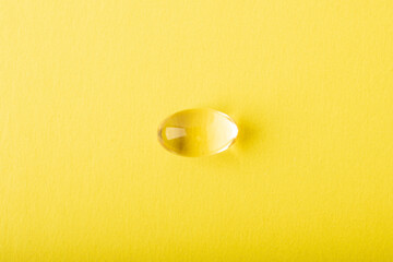 Omega 3 fish oil single close up. Supplement soft capsule isolated on yellow background. Cod liver oil close up. Vitamins in soft capsule. Healthcare concept. Copy space, banner. High quality photo
