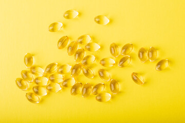 Omega 3 fish oil top wiev. Vitamins in soft capsules on yellow background, cod liver oil. Concept of healthcare, supplements, vitamin D, treatment. Copy space, flatlay, banner. High quality photo
